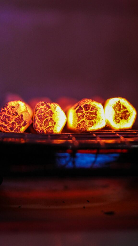 Close-up of glowing charcoal briquettes on a barbecue grill, radiating warmth and heat.